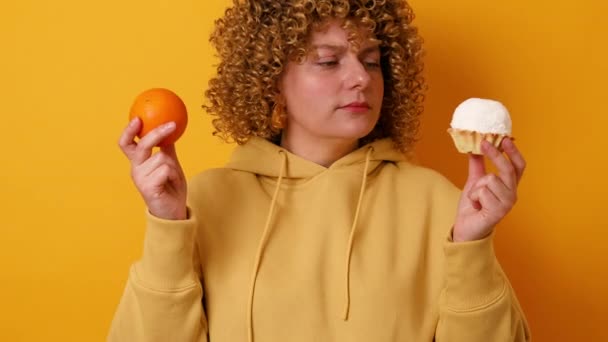 Krásná žena s letní svěží celý oranžový a sladký dort izolované na žlutém pozadí. Zdravé jídlo dobrý vkus. - Záběry, video
