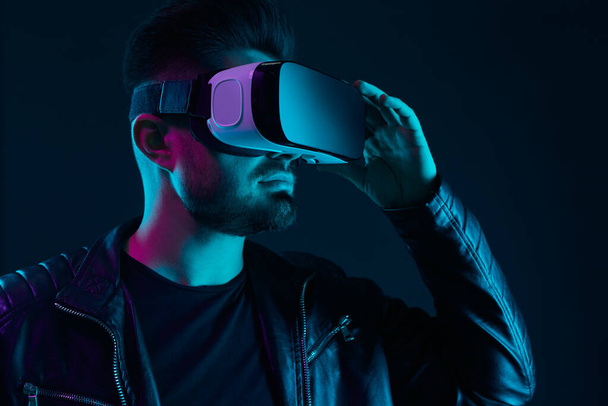 Man experiencing virtual reality in dark room - Фото, изображение