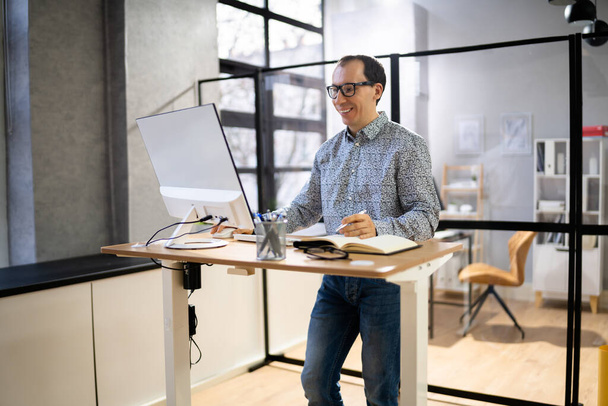 Man Using Adjustable Height Standing Desk In Office For Good Posture - Zdjęcie, obraz