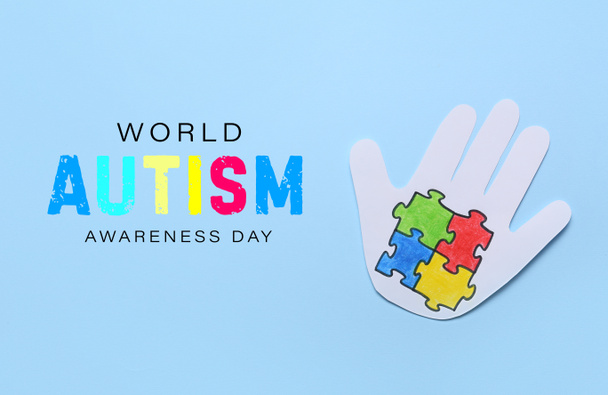 Papieren menselijke palm met kleurrijke puzzelstukjes op blauwe achtergrond. Wereld Autisme Bewustmakingsdag - Foto, afbeelding
