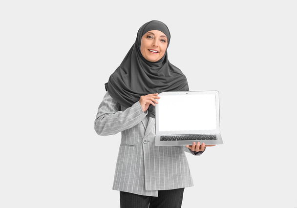 Muslim secretary with laptop on light background - Photo, Image