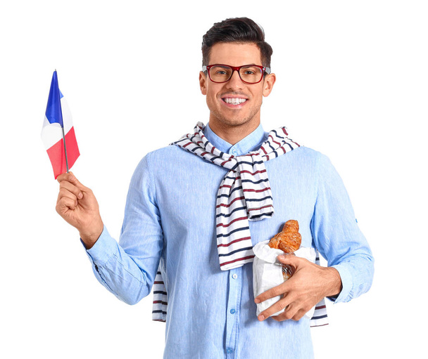 Joven guapo con bandera de Francia y cruasanes aislados en blanco - Foto, imagen