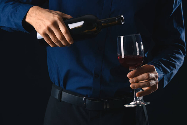 Young male sommelier with wine on dark background, closeup - Foto, afbeelding