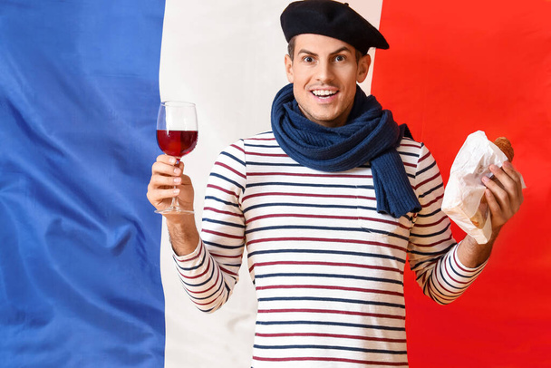 Όμορφος νεαρός με κρασί και κρουασάν στη σημαία της Γαλλίας. - Φωτογραφία, εικόνα