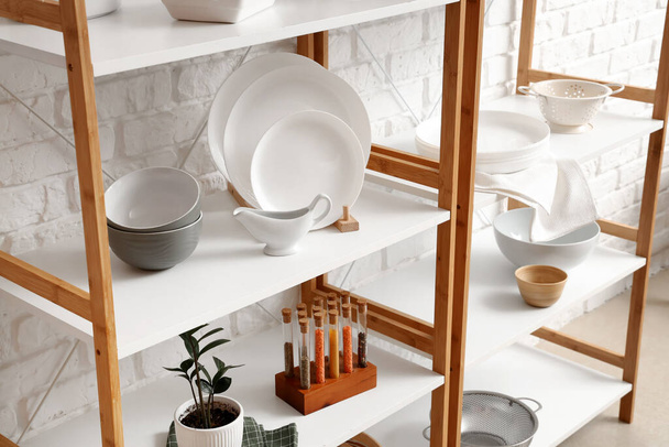 Modern shelf unit with kitchenware near white brick wall - Photo, Image
