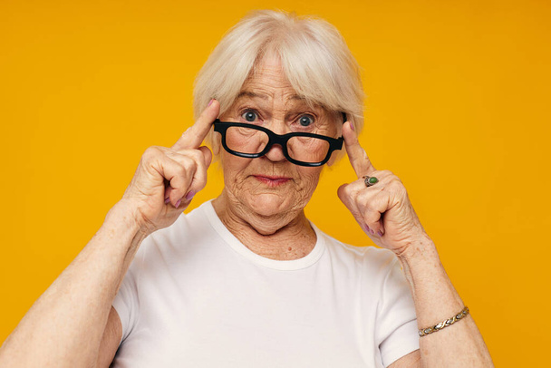 smiling elderly woman in a white t-shirt wears glasses cropped view - Photo, Image