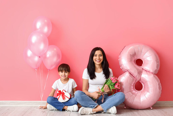 Little son and his mother with gift, bouquet of flowers for International Women's day and balloons on color background - Foto, imagen