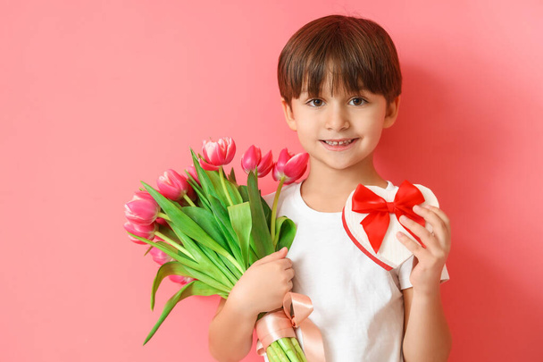 Little boy with gift and bouquet of flowers on color background - Foto, Bild