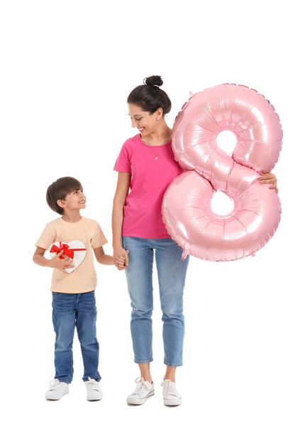 Little son and his mother with gift and balloon in shape of figure 8 on white background. International Women's Day celebration - Photo, Image
