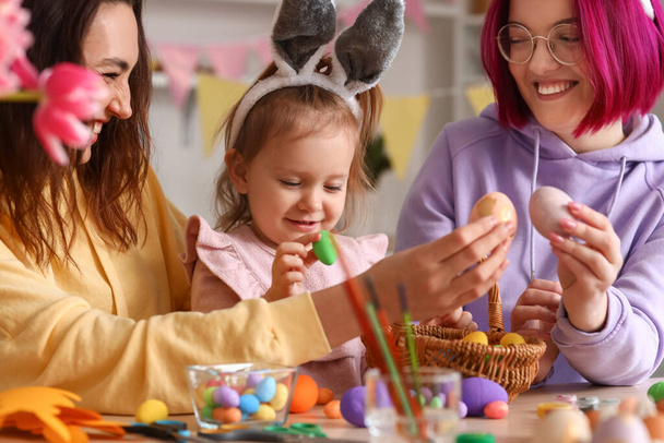 Young lesbian couple with little daughter and Easter eggs in kitchen - Photo, Image