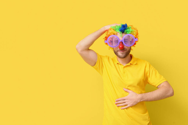 Funny young man in disguise on yellow background. April fools' day celebration - Photo, Image
