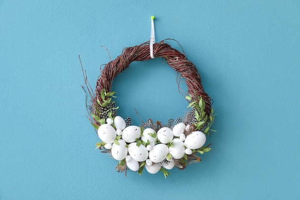 Stylish Easter wreath hanging on color wall - 写真・画像
