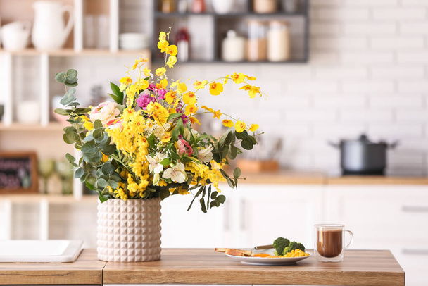 Ваза з різними красивими квітами і сніданком на обідньому столі на кухні
 - Фото, зображення