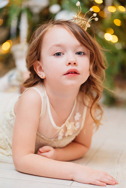 a cute little girl makes a wish and waits for Santa Claus under Christmas tree. - Foto, immagini