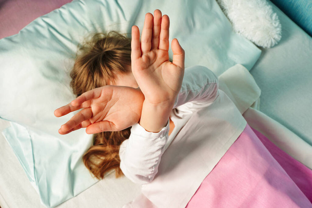 Dormire bambino ragazza copertina viso, braccia incrociate, si rifiuta di svegliarsi al mattino - Foto, immagini