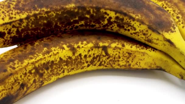 Μερικές αποφλοιωμένες ώριμες μπανάνες σε λευκό φόντο αντίγραφο χώρο, έχει κηλίδες στο δέρμα - Πλάνα, βίντεο