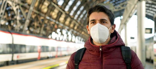 Panorama del joven viajero con máscara protectora en la estación de tren con espacio para copias. Transporte público y concepto de salud. - Foto, imagen