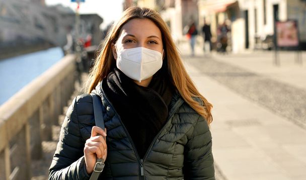 Όμορφη νεαρή γυναίκα φορώντας προστατευτική μάσκα προσώπου περπατά κατά μήκος των καναλιών Navigli στο Μιλάνο, Ιταλία - Φωτογραφία, εικόνα
