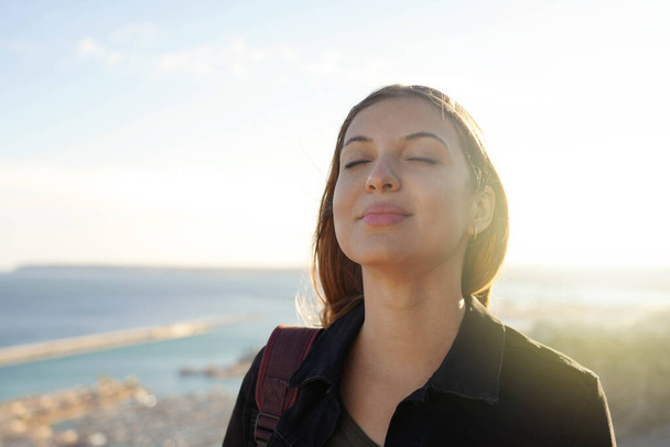 Beautiful young woman with closed eyes breathing relaxing enjoying sun at sunset. Beauty sunshine girl portrait. - Photo, Image