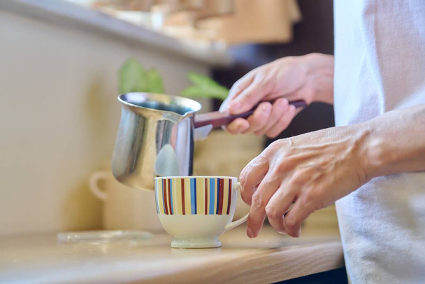 Close-up of a womans hands preparing coffee in an iron cezve. - Φωτογραφία, εικόνα