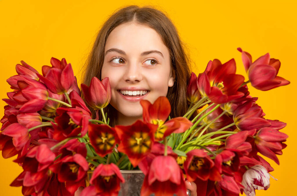 happy girl hold spring tulip flowers on yellow background - Foto, afbeelding