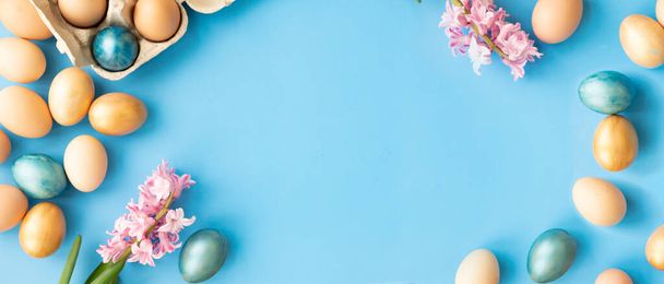 Easter eggs, flowers on blue background. Flat lay, top view, copy space. Easter day. - Foto, Imagen