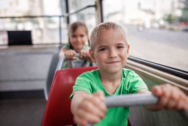 Kids ride in empty tram and look at the window with smile, public transportation, city tramway - Photo, Image