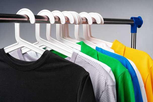 Clothes hang on clothing rack over white background. - 写真・画像