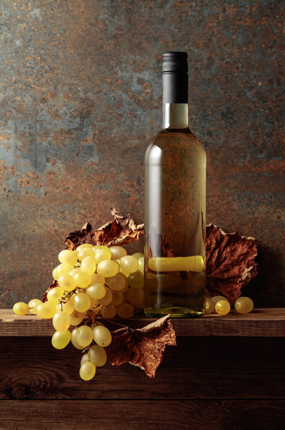 Fehér bor szőlővel és szárított szőlőlevéllel. Régi fa asztal és vintage háttér. Fénymásolási hely. - Fotó, kép