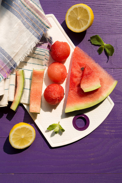 Balls of watermelon lemon mint leaves on a lilac wooden table. Towel in the background. Summer and healthy food concept - Foto, imagen
