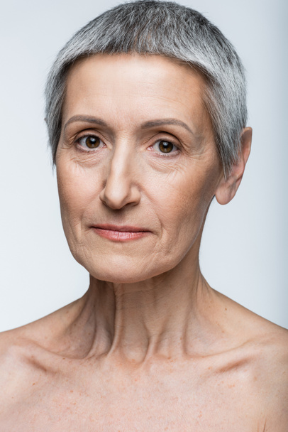 close up of middle aged woman with grey hair isolated on grey - Фото, зображення