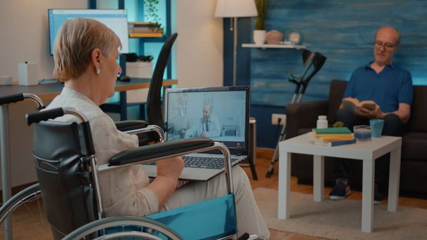 車椅子の高齢女性医師と話をするビデオ通話を使用して - 写真・画像