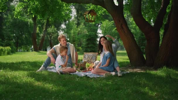 Gelukkig gezin genieten van picknick in het zomerpark. Vrolijke mensen lunchen op gras. - Video