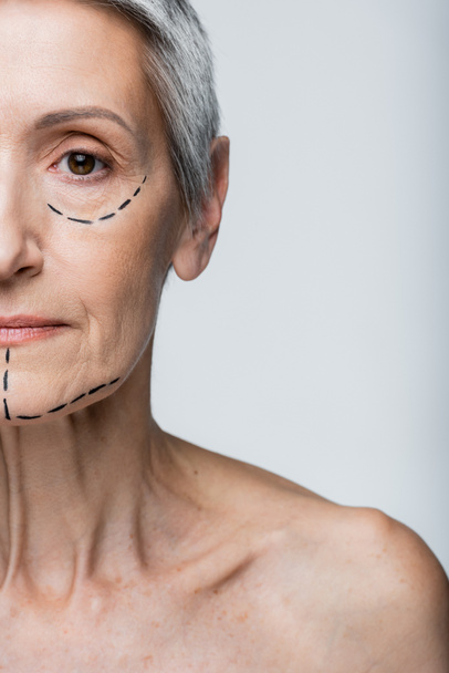 cropped view of mature woman with wrinkles and marked lines on face looking at camera isolated on grey  - Photo, Image