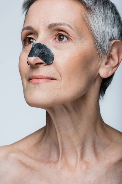 smiling mature woman with grey hair and black patch on nose isolated on grey  - Fotoğraf, Görsel