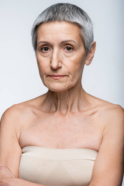 mujer madura con hombros desnudos aislados en gris - Foto, imagen