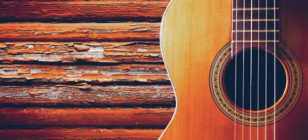 Musical design with acoustic guitar. Spanish guitar and wood wall.Music background - Photo, Image