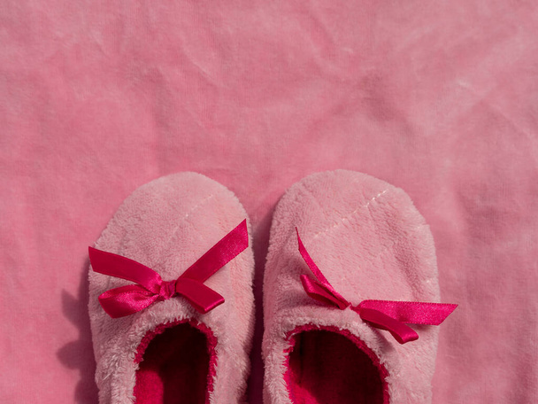 Plush baby's bootees on pink velvet fabric texture top view. Smooth soft fluffy velvety satin cloth girly shiny rose female material surface. Its a Girl Baby Shower Nursery background Expecting mother - Foto, Imagen
