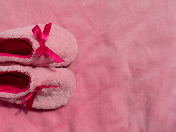 Plush baby's bootees on pink velvet fabric texture top view. Smooth soft fluffy velvety satin cloth girly shiny rose female material surface. Its a Girl Baby Shower Nursery background Expecting mother - Fotoğraf, Görsel