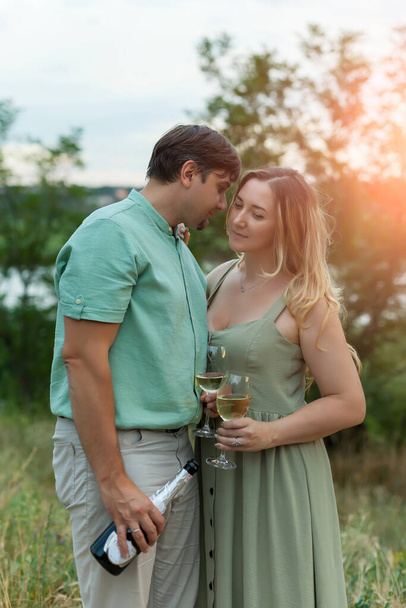 Romantisch stel dat buiten wijnglazen roostert. mooie vrouw klinkende wijn glas met haar man. - Foto, afbeelding