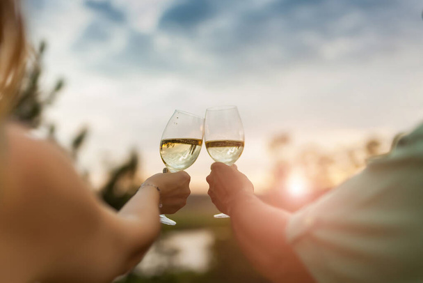 Romantisches Paar stößt im Freien auf Weingläser an. Schöne Frau, die mit ihrem Mann ein Weinglas klingelt. - Foto, Bild