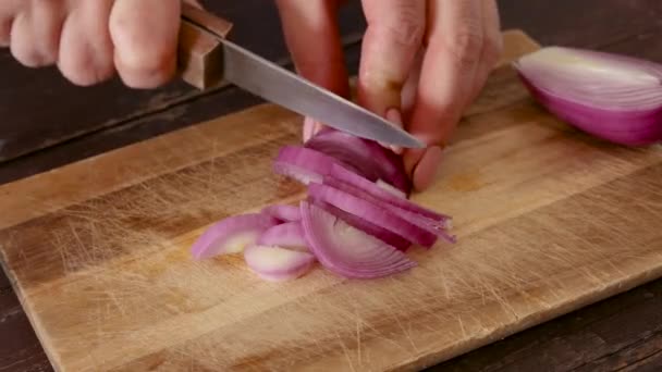 Naisen kädet pilkkovat tuoretta sipulia puulaudalla lähikuva, käsite ruoanlaitto kotona keittiössä - Materiaali, video