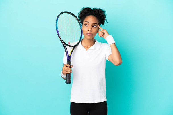 Nuori tennispelaaja nainen eristetty sinisellä taustalla ottaa epäilyksiä ja ajattelua - Valokuva, kuva