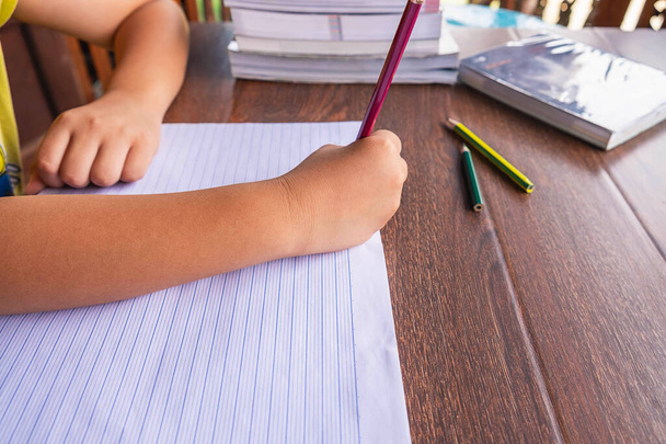 La mano del estudiante está escrita en papel sobre la mesa de la escuela.. - Foto, Imagen