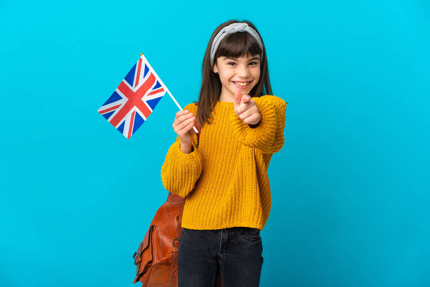 Pieni tyttö opiskelee Englanti eristetty sinisellä taustalla yllättynyt ja osoittaa edessä - Valokuva, kuva