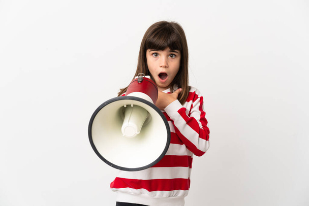 Маленькая девочка на белом фоне кричит через мегафон с удивленным выражением лица - Фото, изображение
