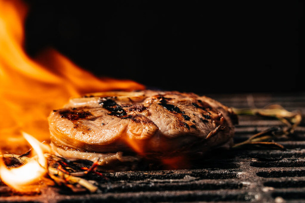 Μοσχάρι μπριζόλες κομμάτια κρέατος στη σχάρα με φλόγες. Αμερικάνικη κουζίνα. Η ιδέα να μαγειρεύεις κρέας. Ιστορικό συνταγών τροφίμων. Κλείσε. τόπος για κείμενο. - Φωτογραφία, εικόνα