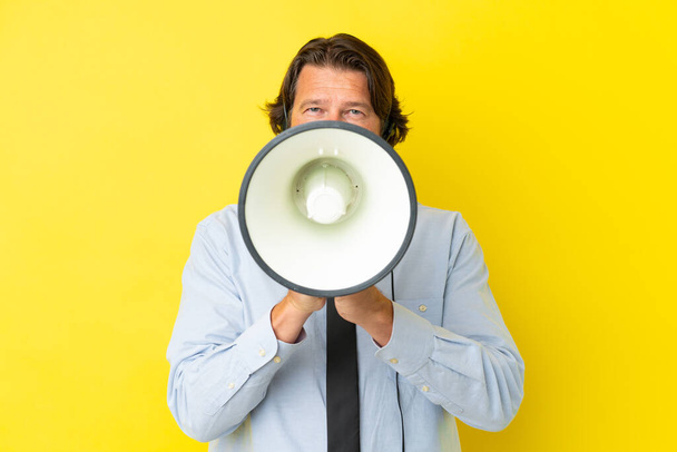Telemarketer dutch man working with a headset isolated on yellow background shouting through a megaphone - Foto, afbeelding