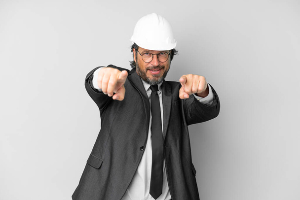 Young architect man with helmet over isolated background points finger at you while smiling - Photo, Image