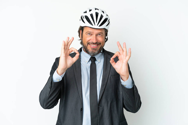Business Senior Mann mit Fahrradhelm isoliert auf weißem Hintergrund zeigt ein ok Zeichen mit Fingern - Foto, Bild